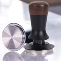 Coffee tamp with wooden top and metal base on a reflective surface