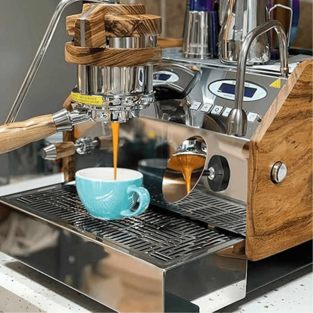 Espresso machine with wooden accents pouring coffee into a blue mug.