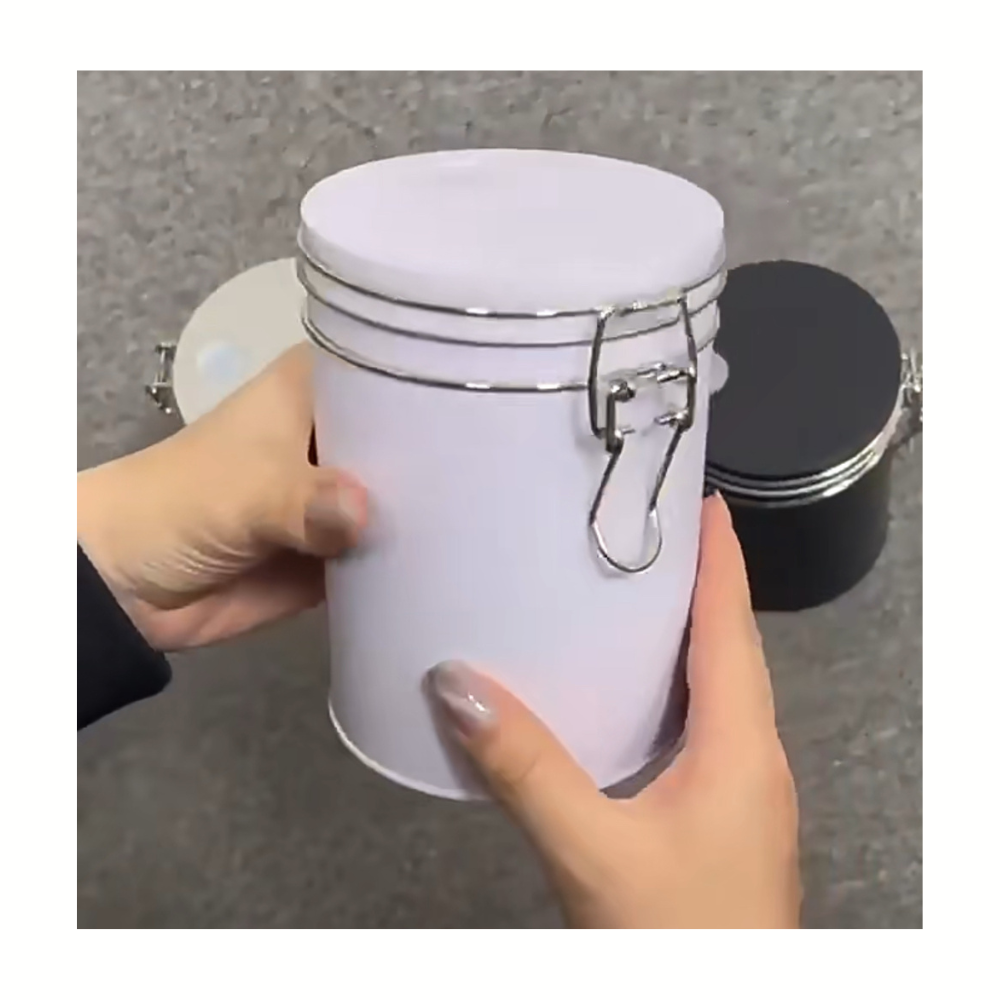 White cylindrical container with a silver clasp held by a hand on a gray background